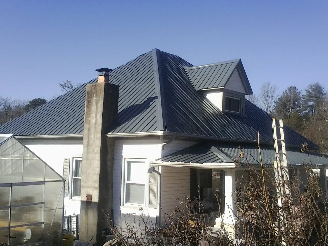 Dark blue standing seam metal roof on a white farmhouse with dormer — Slate & Tile Roof Repair by Roofing Brothers in Nyssa