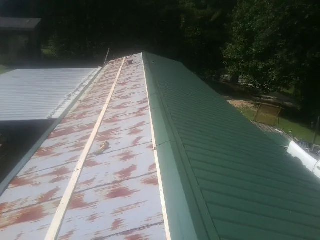 Old rusted panels beside newly installed green metal roofing — Wind Damage Roof Repair by Roofing Brothers in Nyssa