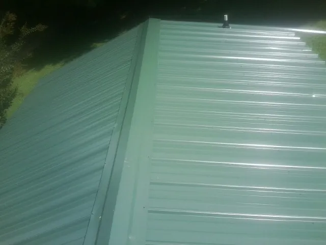 New green metal panels meeting at the ridge of a roof — Flat Roof Repair work by our crew in Nyssa