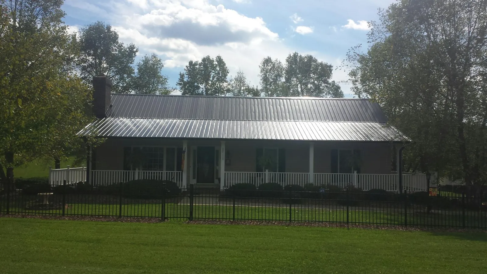 Gray metal roof on a brick ranch with a full width front porch — Gutter Guard Installation work by our crew in Nyssa