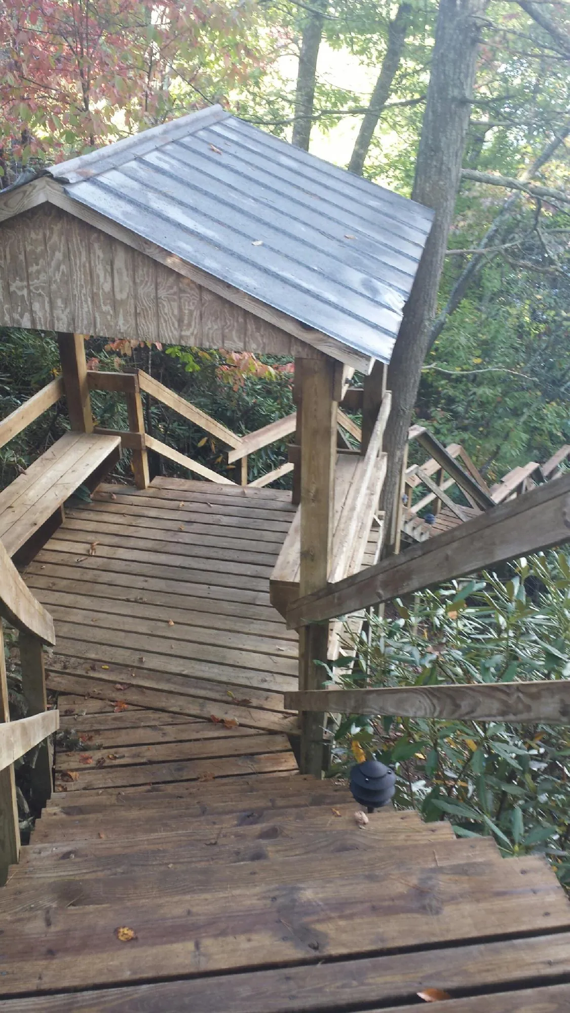 Metal roofed shelter over wooden steps on a wooded walkway — Skylight Repair & Installation work by our crew in Nyssa