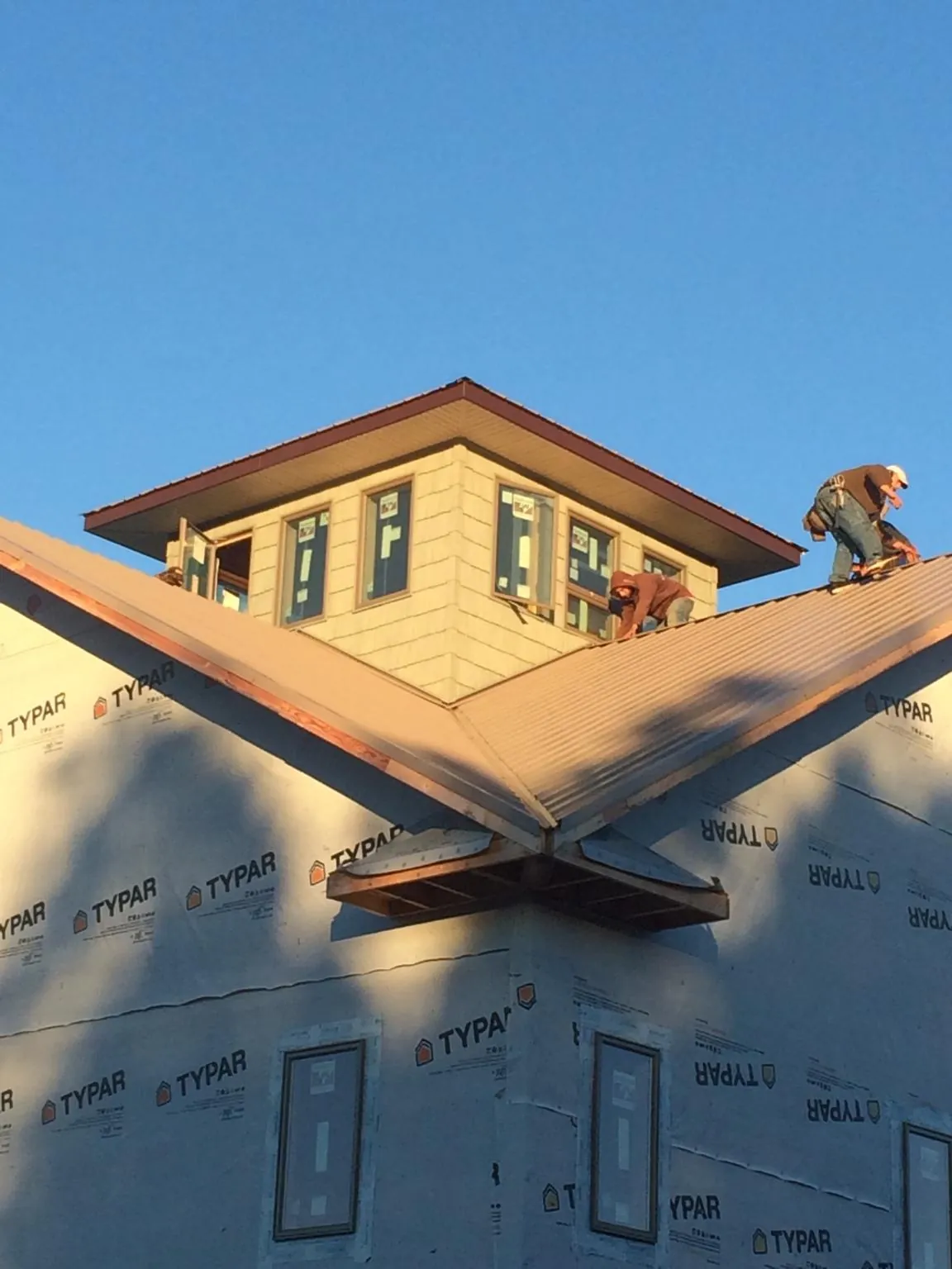 Roofers working around a rooftop cupola on a new metal roof at sunset — Roof Waterproofing in Nyssa by Roofing Brothers
